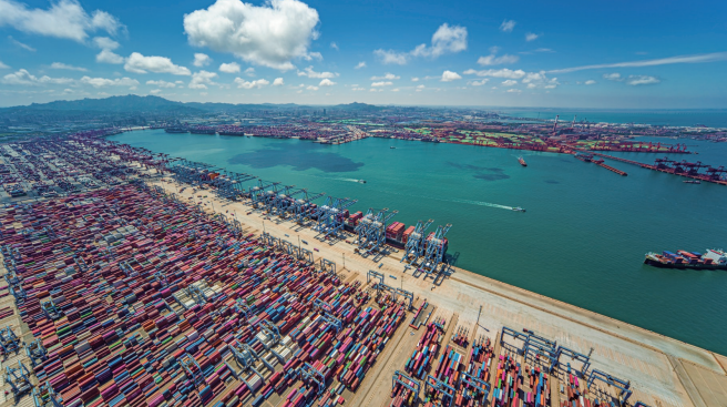 山东港口青岛港前湾港区，大型集装箱货轮正在繁忙地进行靠离泊作业。